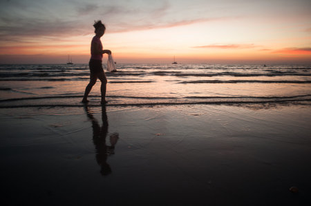 Lanta in Krabi, Thailand - February 2, 2014: The locals on the beach looking for molluscs, during low tide at sunset sky background.のeditorial素材