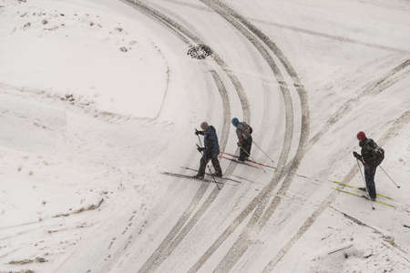Saint-Petersburg, Russia - February 27, 2016: Three skiers cross the muddy footprints of cars. Top view, winter, snow.のeditorial素材