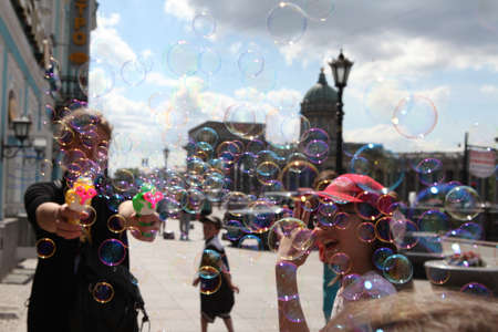 Saint-Petersburg, Russia - February 4, 2015: The girl starts up soap bubbles on the background of the main city sights - Kazan Cathedral. Summer sunny dayのeditorial素材