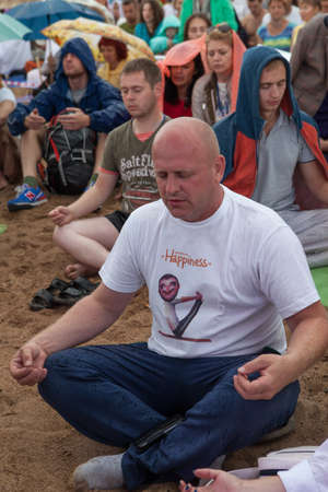 Saint-Petersburg, Russia - 8 August 2015: The mass meditation in a city park under the guidance of a yoga guru. Large numbers of people meditating in a park outdoors in summerのeditorial素材
