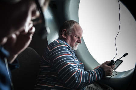 Saint-Petersburg, Russia - April 28, 2015: A middle-aged man adjusts cosmic connection on the phone during the flight by the large windows of the transport aircraft MO. Phone space communicationのeditorial素材
