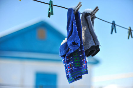 Old worn socks on clothesline dried in winter sunny day.