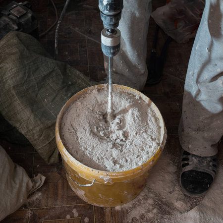 Construction worker man stirs the mixture in the bucket construction for alignment and putty walls...