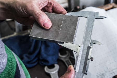 Control the size of the metal parts with a caliper measuring device. Shop metalworking plant.の写真素材