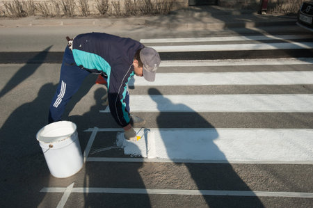 Saint-Petersburg, Russia - April 6, 2016: Road workers doing markup crosswalk with white paintのeditorial素材