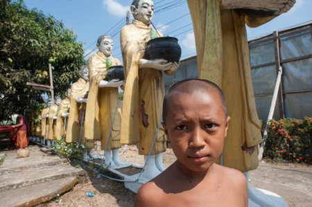 Myanmar, Kawthaung - March 9, 2014: Buddhist monks yunnye on the background of the sculptural composition - a group of monks go for a meal.のeditorial素材
