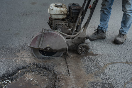Worker cuts a piece of asphalt using a cutting machine pavement. The machine for cutting asphalt....