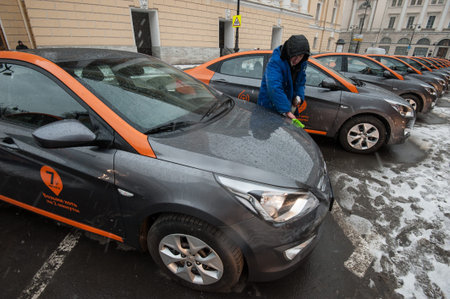 Saint-Petersburg, Russia - January 30, 2017: cars-sharing - the opening of a new service car rental per minute. employee wipes car windshieldのeditorial素材