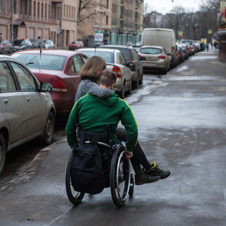 Saint-Petersburg, Russia - February 18, 2017: A handsome disabled young man  in a wheelchair with  girl on the streetのeditorial素材