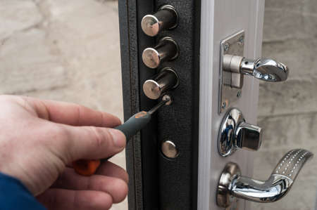 The carpenter installs a reliable burglar-resistant lock in the metal door.の写真素材