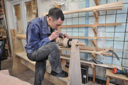 St. Petersburg, Russia - August 8, 2017: A new manufactory for the full cycle of production of a harp musical instrument. The wood carver enchants the base of the musical instrument.のeditorial素材