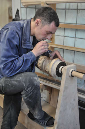 St. Petersburg, Russia - August 8, 2017: A new manufactory for the full cycle of production of a harp musical instrument. The wood carver enchants the base of the musical instrument.のeditorial素材
