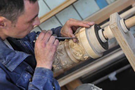 St. Petersburg, Russia - August 8, 2017: A new manufactory for the full cycle of production of a harp musical instrument. The wood carver enchants the base of the musical instrument.のeditorial素材