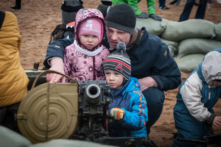 St. Petersburg, Russia - April 30, 2017: Children play with a machine gun at a military technology festival in the city park.のeditorial素材