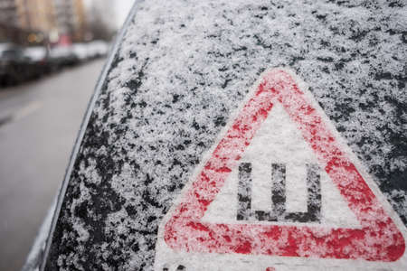 Car sticker on the rear snow-covered glass of the car warning drivers that the car is fitted with wheels with studded rubberの写真素材