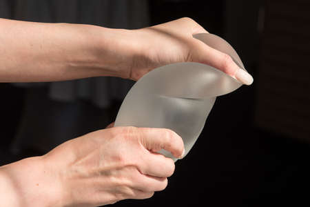 Demonstration of the properties of elasticity, softness, strength, reliability of silicone breast implant, used in plastic surgery to increase or enhance sexuality, aesthetic appeal of formsの写真素材