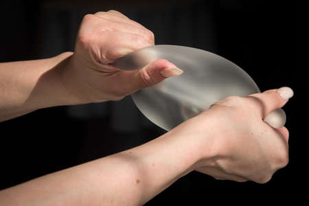 Demonstration of the properties of elasticity, softness, strength, reliability of silicone breast implant, used in plastic surgery to increase or enhance sexuality, aesthetic appeal of formsの写真素材