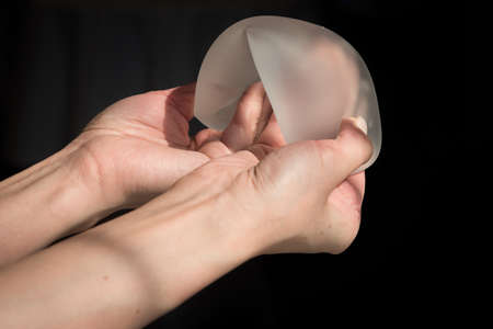 Demonstration of the properties of elasticity, softness, strength, reliability of silicone breast implant, used in plastic surgery to increase or enhance sexuality, aesthetic appeal of formsの写真素材