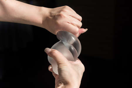 Demonstration of the properties of elasticity, softness, strength, reliability of silicone breast implant, used in plastic surgery to increase or enhance sexuality, aesthetic appeal of formsの写真素材