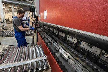 St. Petersburg, Russia - June 29, 2016: A shop for processing steel, aluminum and zinc sheets used to build the bodies of subway cars at a transport engineering plant. The worker controls the work of the machine.のeditorial素材