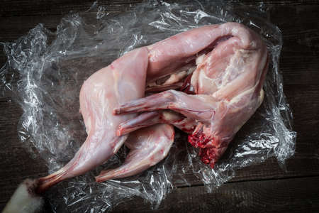 A whole cut-up, fresh rabbit on a wooden natural table lies before the finish cut for cooking delicaciesの写真素材