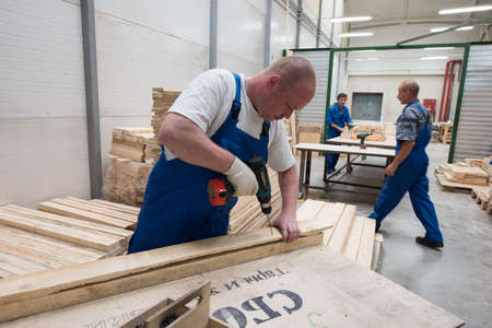 St. Petersburg, Russia - June 29, 2016:Carpenters make a container in the warehouse of a factory for the production of furniture and design elements for electric trains.のeditorial素材