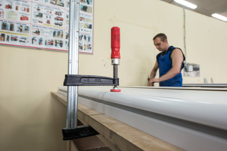 St. Petersburg, Russia - June 29, 2016: The worker fastened the clamp to the furniture parts for their reliable gluingのeditorial素材
