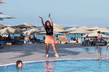 Hurghada, Egypt - December 2, 2014: Tourists are resting on the beach of the Red Sea. The animator conducts an entertaining dance physical culture event by the pool with fresh water.のeditorial素材