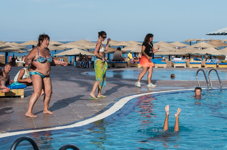 Hurghada, Egypt - December 2, 2014: Tourists are resting on the beach of the Red Sea. The animator conducts an entertaining dance physical culture event by the pool with fresh water.のeditorial素材