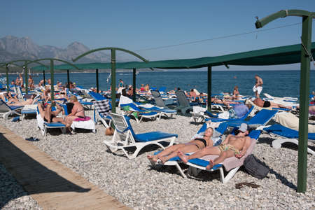 Kemer, Turkey - October 22, 2017: Tourists are resting on the beach of Kemer. Adult men and women sunbathe on the deck chairs under the awning.のeditorial素材