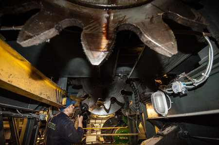 St. Petersburg, Russia - March 15, 2016: Repair of the underground escalator. A worker with a lantern inspects the gear-box.のeditorial素材