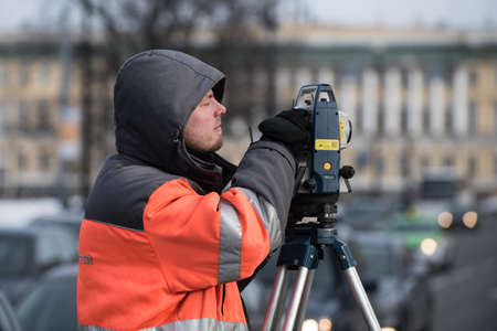 St. Petersburg, Russia - March 28, 2018: A young male surveyor makes the necessary measurements in the city center for the purpose of improving the road and sidewalks.のeditorial素材