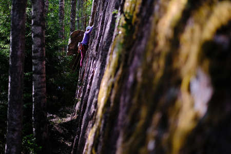 Leningrad region, Russia - June 23, 2018: Climbers during training sessions on overcoming rocky mountains on the rocks "Paltsevo". The climber overcomes steep areas with the help of equipment.のeditorial素材