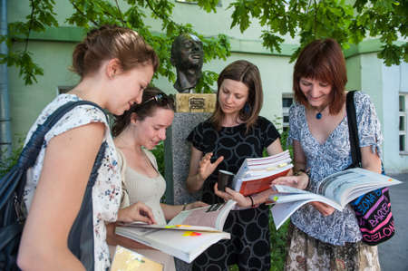St. Petersburg, Russia - June 10, 2018: a young beautiful attractive girl - a university teacher explains to students female study material in the inner courtyard of the university.のeditorial素材