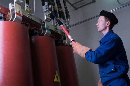 St. Petersburg, Russia - April 19, 2016: Electrician specialist conducts maintenance work on a high voltage transformer. Long probe fixes the wires for grounding.のeditorial素材