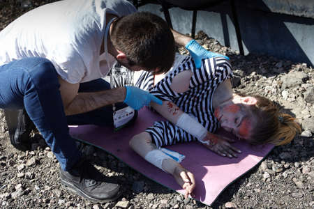 St. Petersburg, Russia - May 12, 2018: contest / exercises on first aid at the pre-hospital stage. A young man provides first aid to a girl who has received multiple skin lesions.のeditorial素材