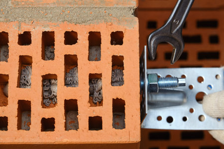 Stage of installation of a chemical anchor in a red building brick with cellular voids.  Fastening...