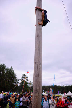 Leningrad Region, Russia - June 30, 2018: Sabantuy - the Peopleâs Tatar and Bashkir feast of the end of spring fieldwork. Climbing up the pillar.のeditorial素材