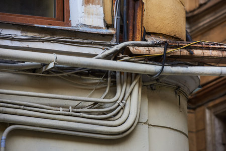 Wires - electrical, telephone, antenna, computer, network on the wall of a dilapidated house with...