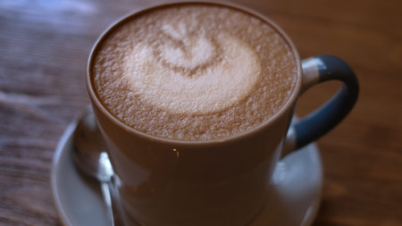 A cup of coffee on a saucer with art pattern made with whipped cream. Coffee - Kortado Italian...