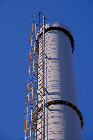 New modern exhaust pipe in an old residential area with low-rise buildings against a clean blue sky....