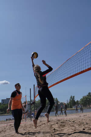 St. Petersburg, Russia- June 30, 2019: Beach volleyball sports. Young handsome man kicks the ball. City holiday. Sunny day.のeditorial素材