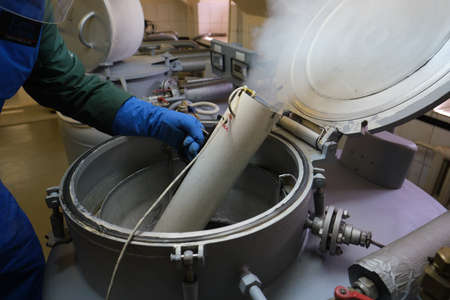St. Petersburg, Russia - April 23, 2019: An employee of the scientific research institute in special uniforms protected from liquid nitrogen works in containers where rare plant seeds are stored.のeditorial素材