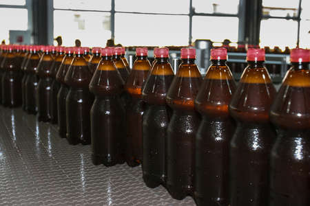 St. Petersburg, Russia - June 21, 2006: Production line of the brewery. There are plastic liter bottles with dark beer on the conveyor. Quality control.のeditorial素材