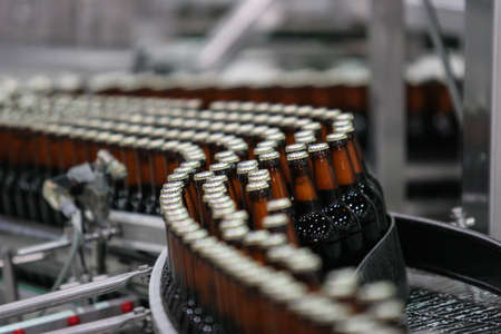 St. Petersburg, Russia - June 21, 2006: Production line of the brewery. Dark beer in glass brown transparent bottles without labels on the conveyor.のeditorial素材