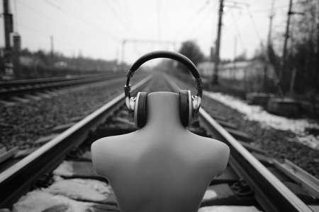 Headless mannequin in headphones near the railroad tracks, conceptual look at the danger of objects while listening to music on the street. Leather trim, high quality and attractive earpieceの写真素材