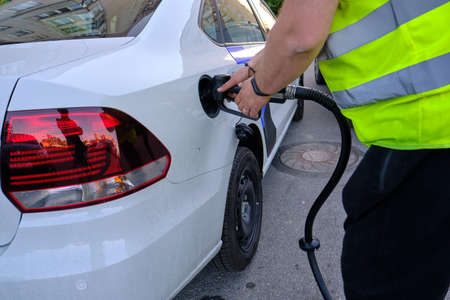 St. Petersburg, Russia - June 18, 2019: The driver of a gas station refuel the car of the client who called for road assistance. Refueling gun. Green vest with reflective elementsのeditorial素材