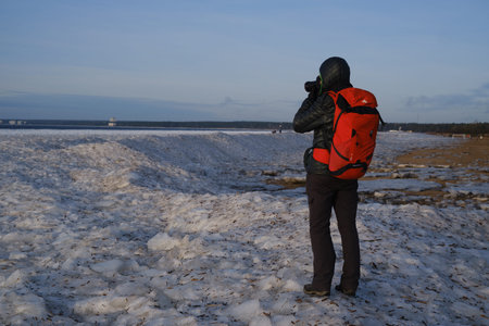 St. Petersburg, Russia - January 2, 2020: Tourists stroll along the coast of the Gulf of Finland. Sunny, fine day after a hurricane and an ice storm. Pieces of ice, open space, skyline. Russian crazy extremeのeditorial素材