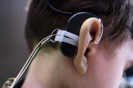 Hearing aid in the ear of a boy of 6-7 years old at a doctor's appointment. Auditory testing and selection of treatment methods using auditing equipment. Faces are unrecognizable.の写真素材