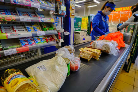 St. Petersburg, Russia - April 10, 2020: Supermarket cashier serves customers during a pandemic. Cash machine. Sales receipt. Shipping tape. Productのeditorial素材